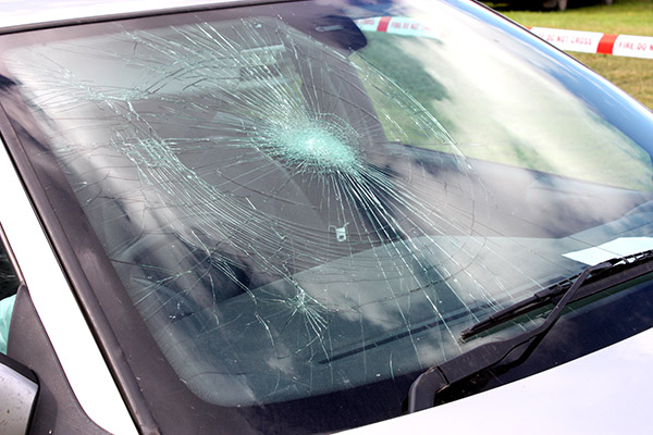 A windshield with a spider-web-looking crack in it.