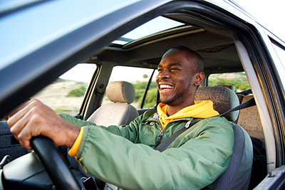 A man in a green jacket smiling as he drives away.